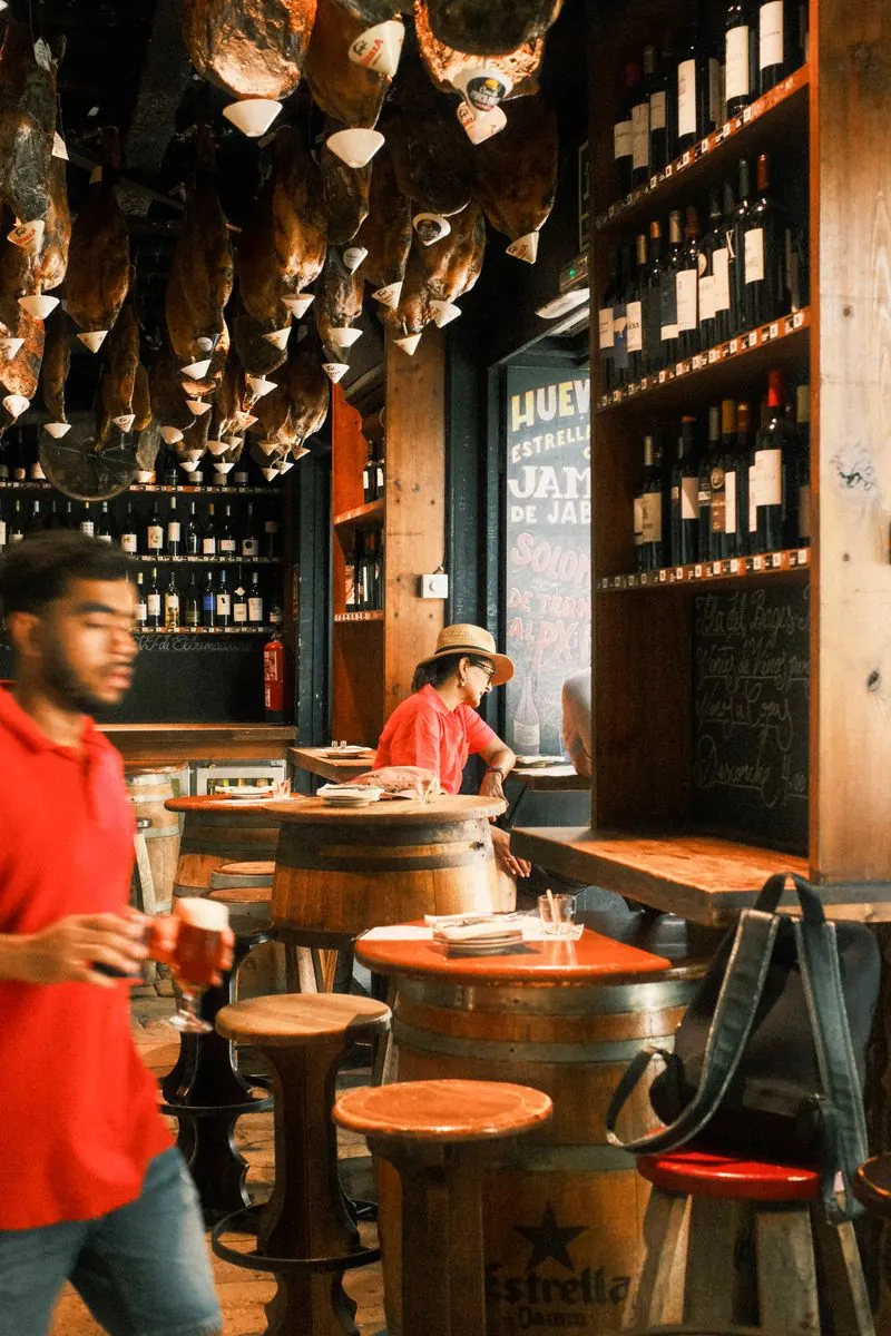 Clientes en una taberna tradicional con jamones y vinos